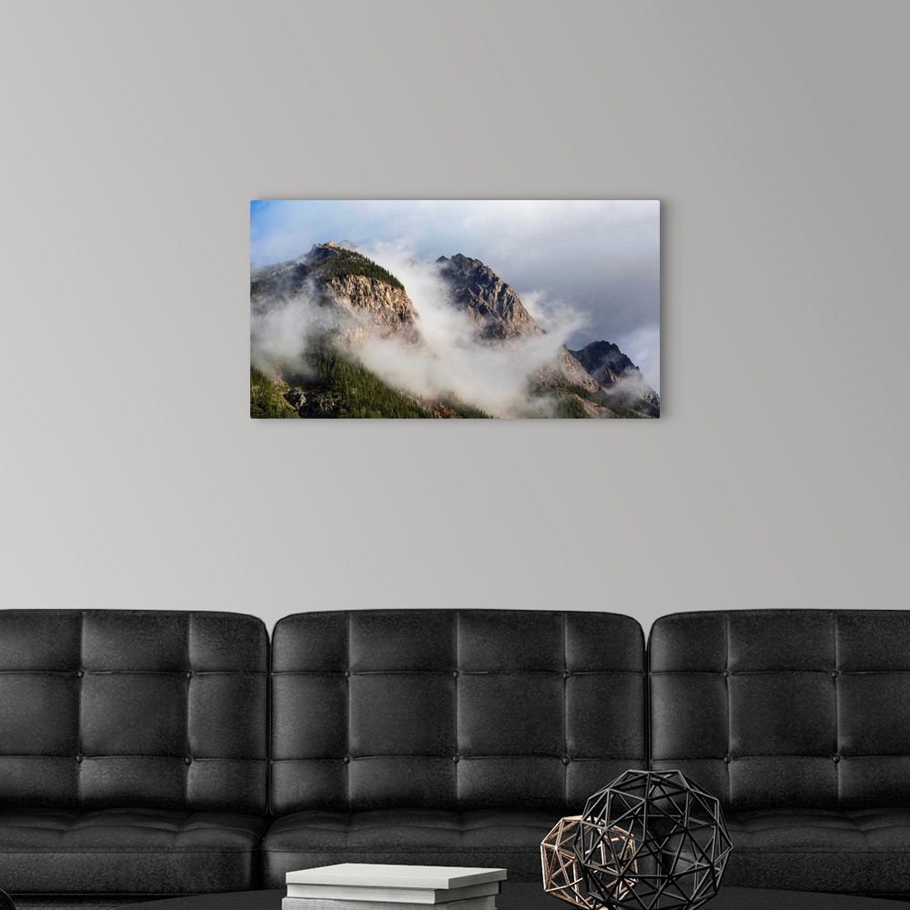 A modern room featuring Clouds gather around rocky mountain peaks, field, British Columbia, Canada.