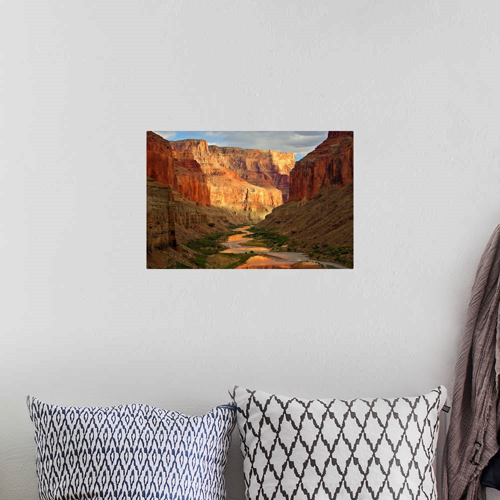 A bohemian room featuring Large wall art of a river winding through the bottom of the Grand Canyon while the sides of the c...