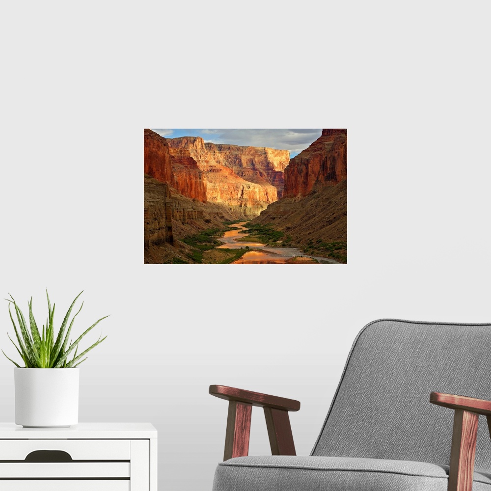A modern room featuring Large wall art of a river winding through the bottom of the Grand Canyon while the sides of the c...