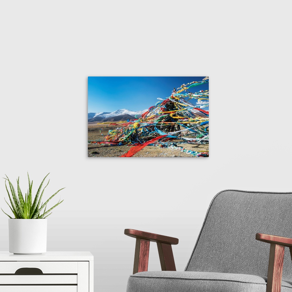 A modern room featuring Colourful Tibetan prayer flags (Lung ta) under the strong wind with white mountain tops in the ba...