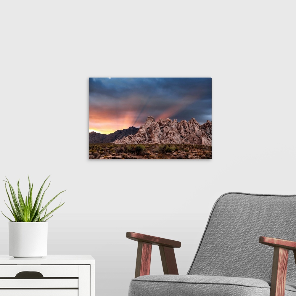 A modern room featuring Crepuscular rays at sunset behind rock formations in the Mojave Desert, Kelso, California, United...