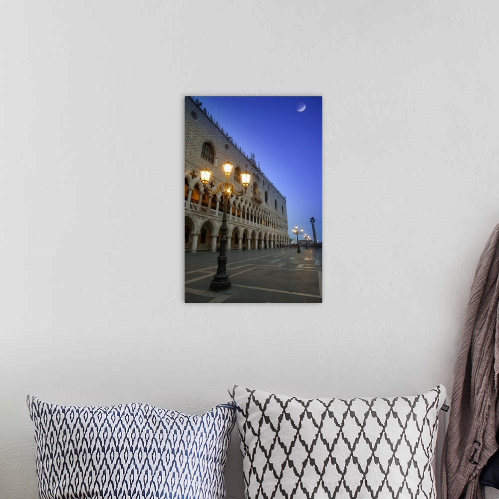 A bohemian room featuring Doge's Palace at dusk with illuminated lamp posts and a moon in the blue sky; Venice, Italy