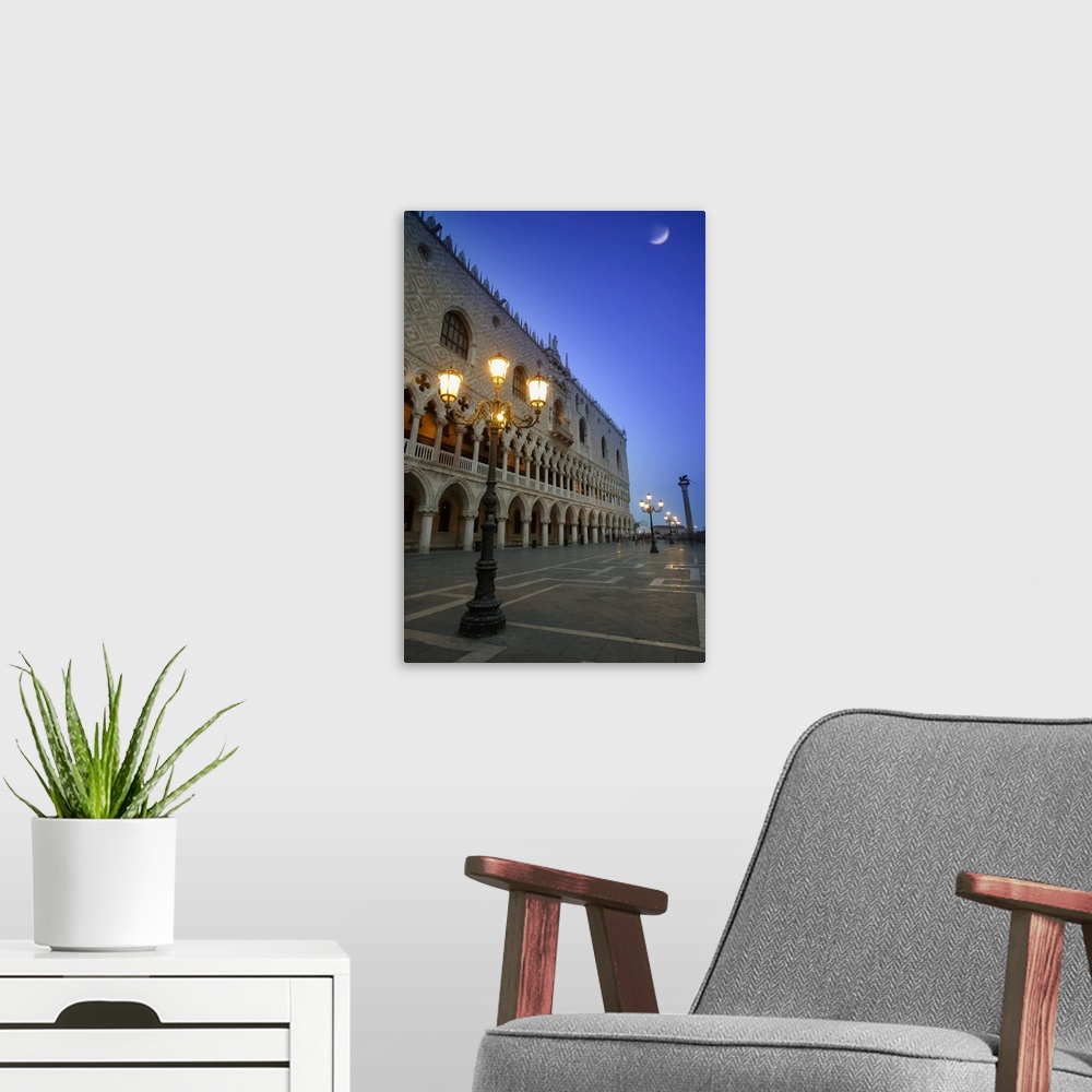 A modern room featuring Doge's Palace at dusk with illuminated lamp posts and a moon in the blue sky; Venice, Italy