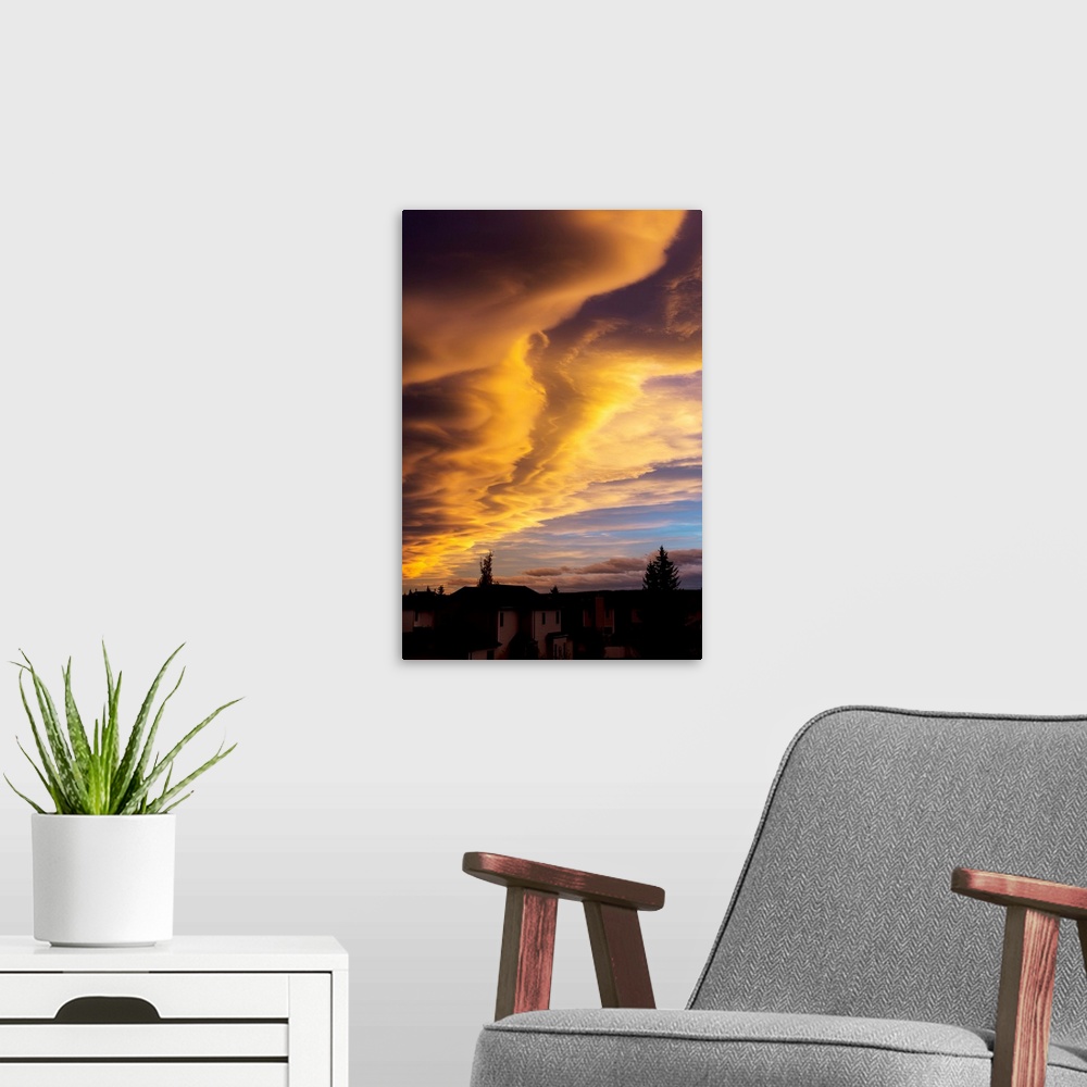 A modern room featuring Dramatic colourful clouds at sunset with interesting formations and some blue sky with houses in ...