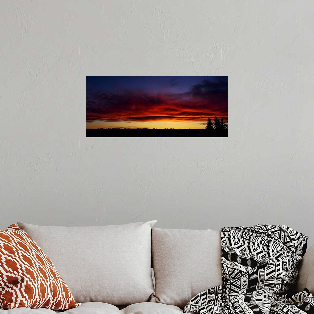 A bohemian room featuring Dramatic colourful sky/clouds at sunset with silhouette trees and mountain range in background; C...