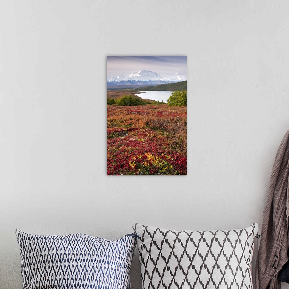 A bohemian room featuring A vertical photograph of an Alaskan mountain and valley in the distance viewed from across a lake...