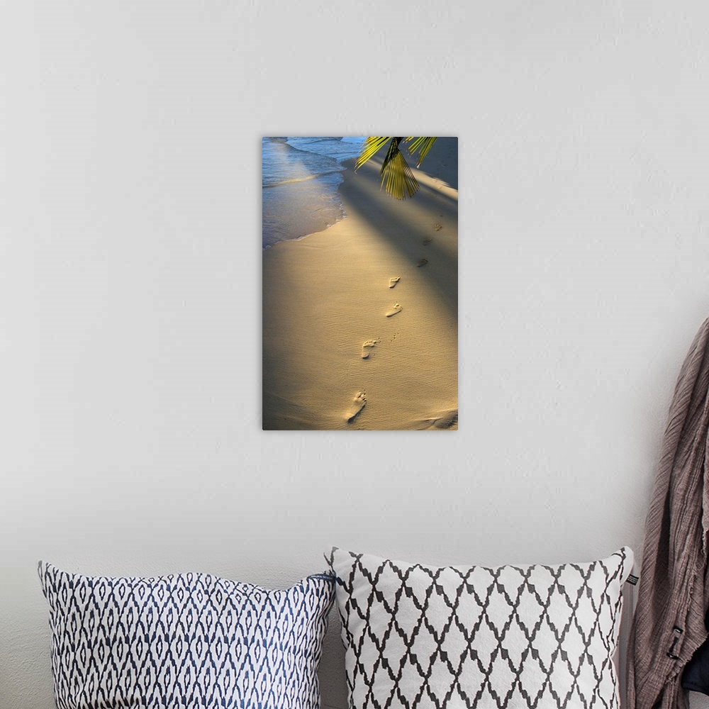 A bohemian room featuring Vertical photograph on a large wall hanging of a single row of footprints in the sand, near the s...