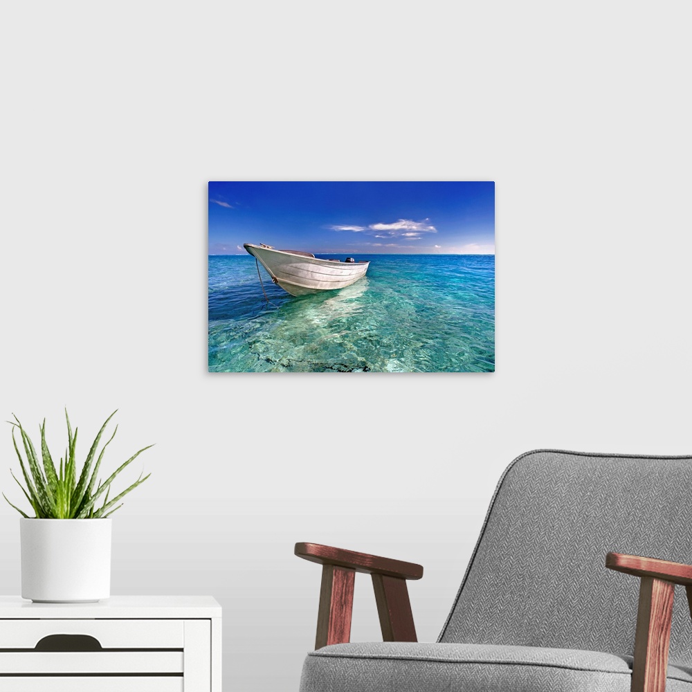 A modern room featuring An image print of a wooden boat floating in a crystal clear ocean.