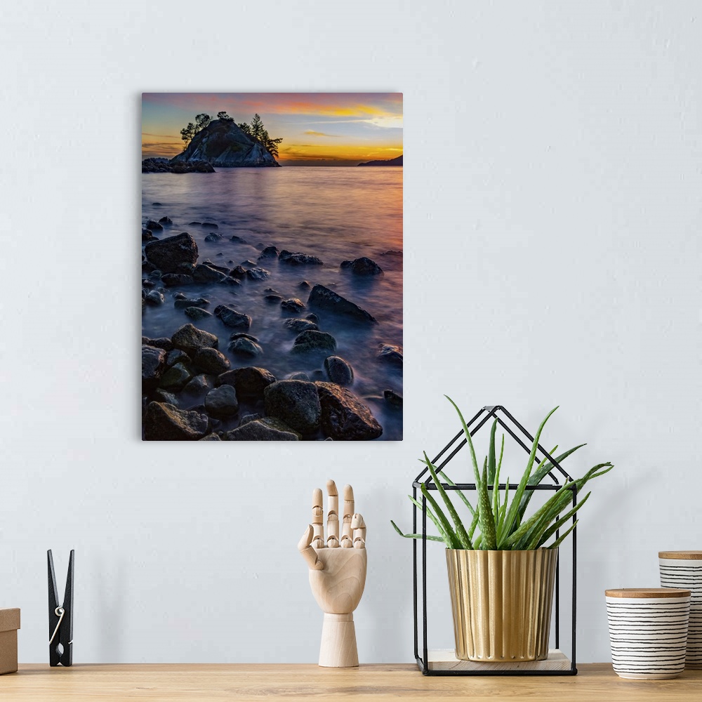 A bohemian room featuring Golden sunlight illuminating the clouds in the distance and wet rocks along the shoreline; Vancou...
