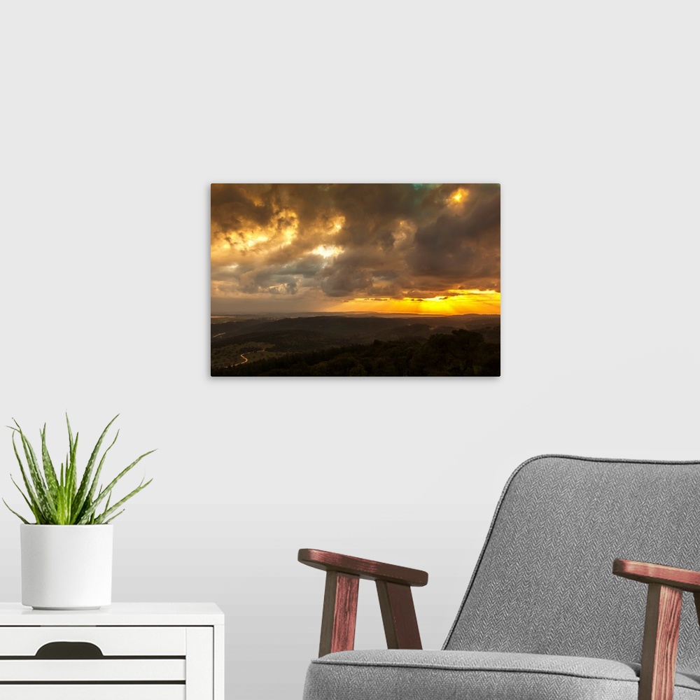 A modern room featuring Golden sunset with glowing clouds and silhouetted landscape. Israel.