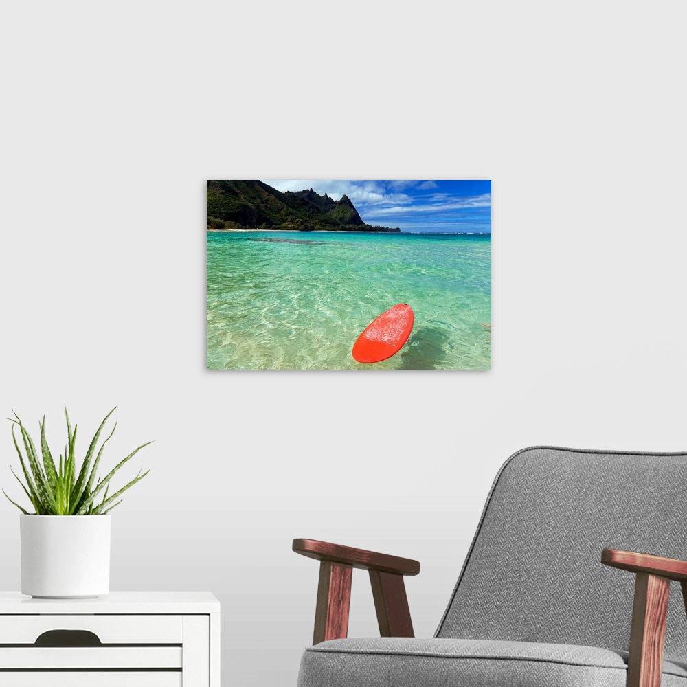 A modern room featuring Photograph of bobbing surfboard in ocean with crystal clear waters and a small beach with tree co...