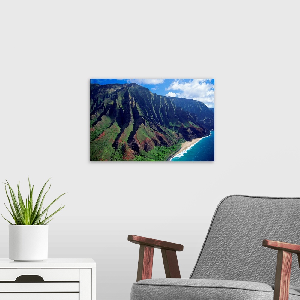 A modern room featuring This large piece is an aerial photograph of huge mountains on the coast of a Hawaiian island.