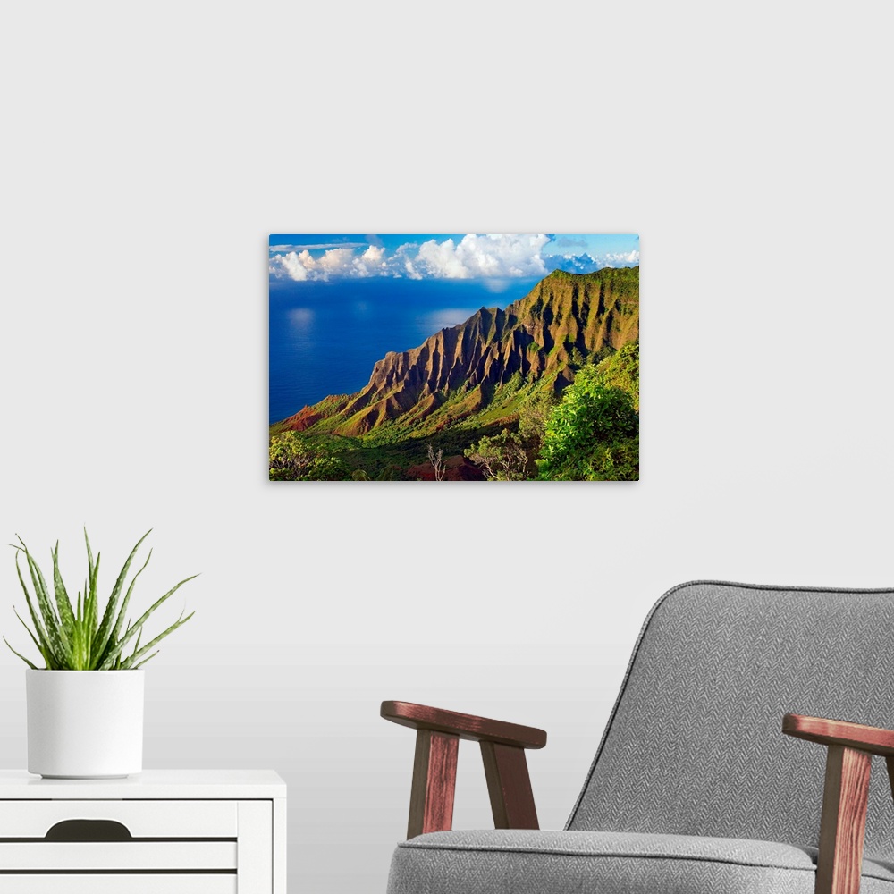 A modern room featuring This is a landscape photograph of mountain cliffs on a view down a hillside to the ocean and cumu...