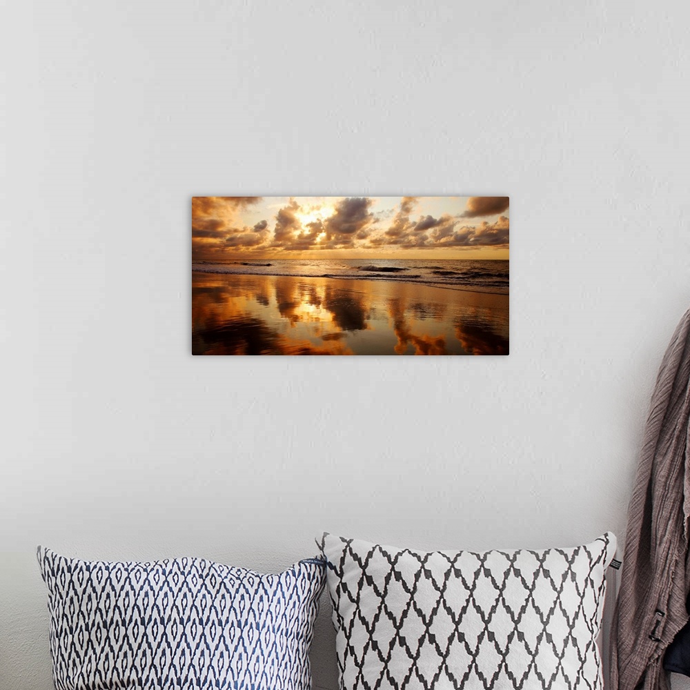 A bohemian room featuring Panoramic photograph of seashore at dusk.  There is standing water on the beach and waves rolling...