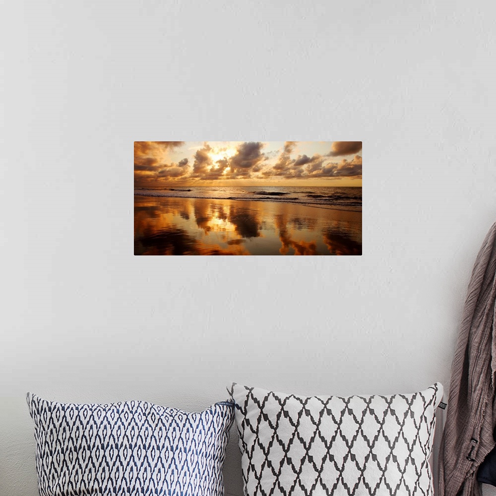 A bohemian room featuring Panoramic photograph of seashore at dusk.  There is standing water on the beach and waves rolling...