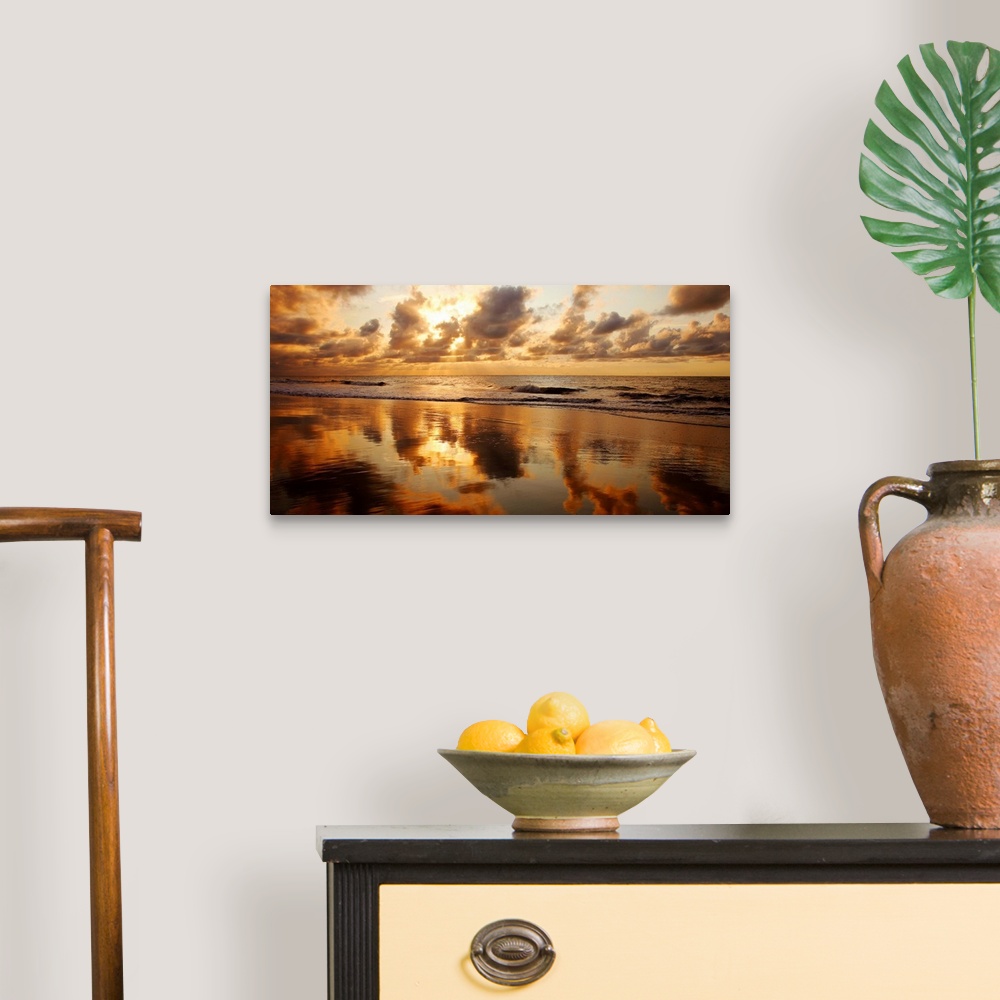 A traditional room featuring Panoramic photograph of seashore at dusk.  There is standing water on the beach and waves rolling...