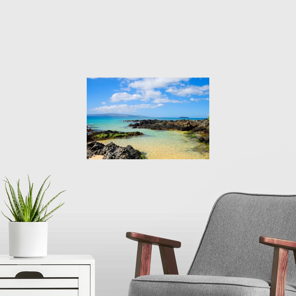 A modern room featuring Photograph of rocky shoreline with crystal clear water and mountains in the distance under a clou...