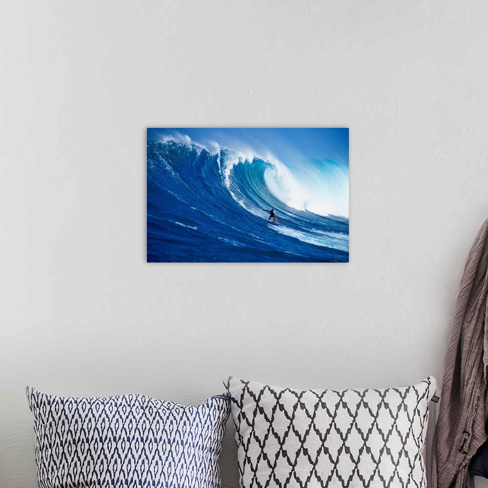 A bohemian room featuring A lone figure on a surfboard coasts down the side of a huge wave as it crests over him, filling t...