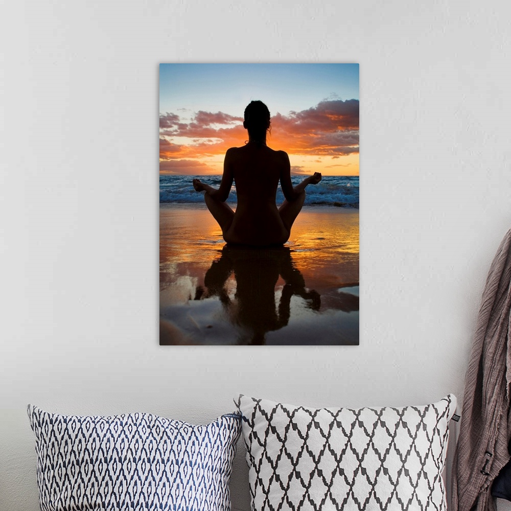 A bohemian room featuring Woman meditating and doing yoga on the wet sand as the surf breaks in front of her and the sun se...