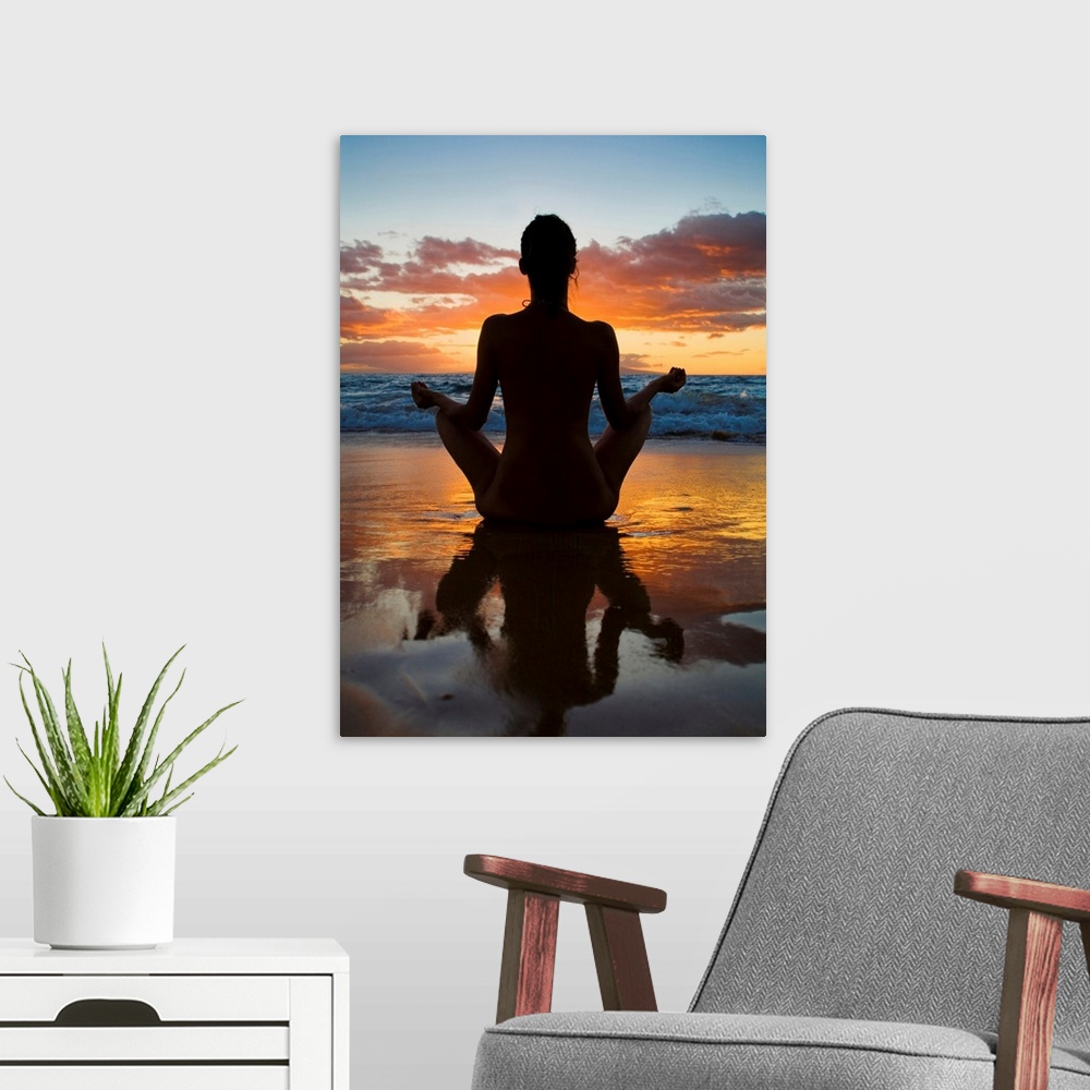 A modern room featuring Woman meditating and doing yoga on the wet sand as the surf breaks in front of her and the sun se...