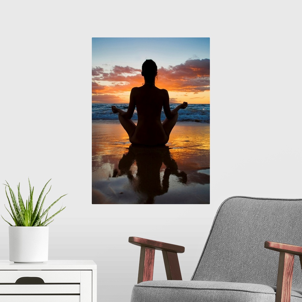 A modern room featuring Woman meditating and doing yoga on the wet sand as the surf breaks in front of her and the sun se...