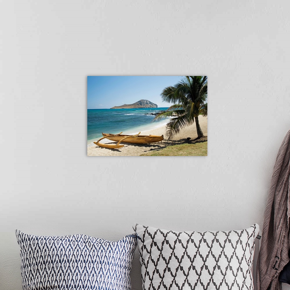 A bohemian room featuring Landscape photograph on a giant canvas of a koa canoe sitting beneath a palm tree, along the East...
