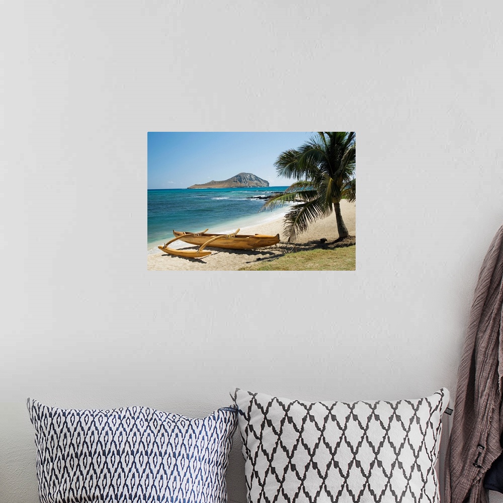 A bohemian room featuring Landscape photograph on a giant canvas of a koa canoe sitting beneath a palm tree, along the East...