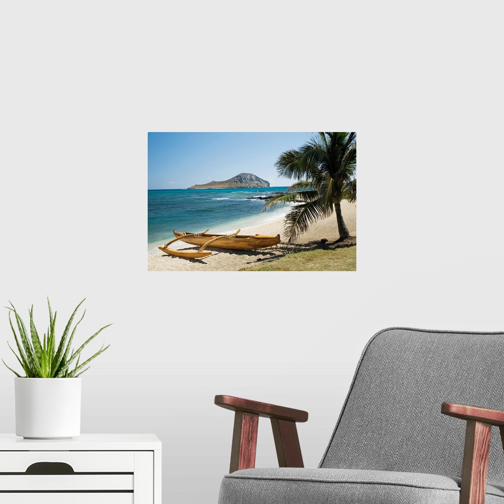 A modern room featuring Landscape photograph on a giant canvas of a koa canoe sitting beneath a palm tree, along the East...