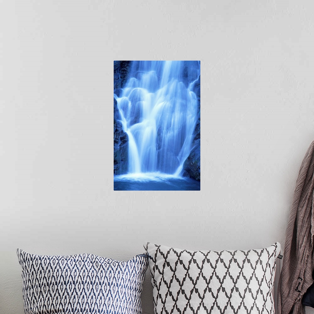 A bohemian room featuring Vertical canvas of a big waterfall rushing down a rocky cliff in Hawaii.