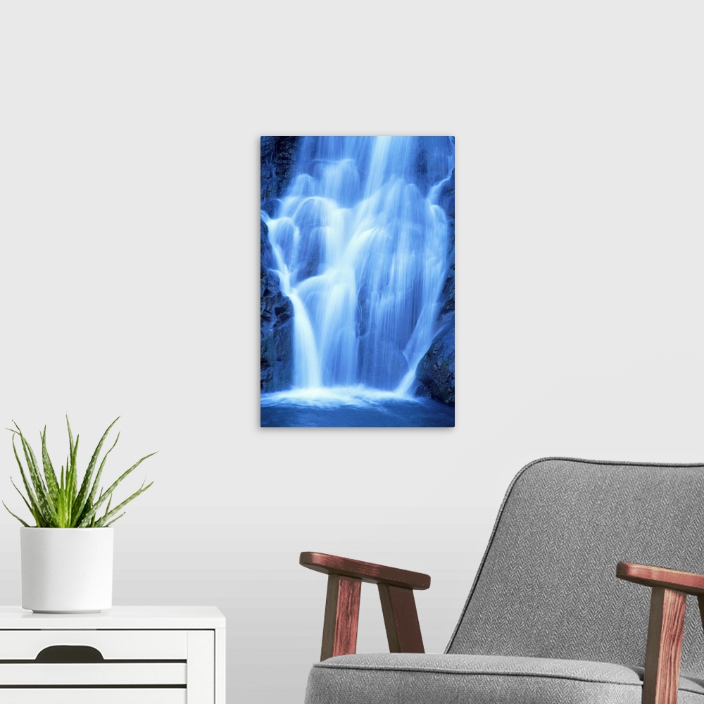 A modern room featuring Vertical canvas of a big waterfall rushing down a rocky cliff in Hawaii.