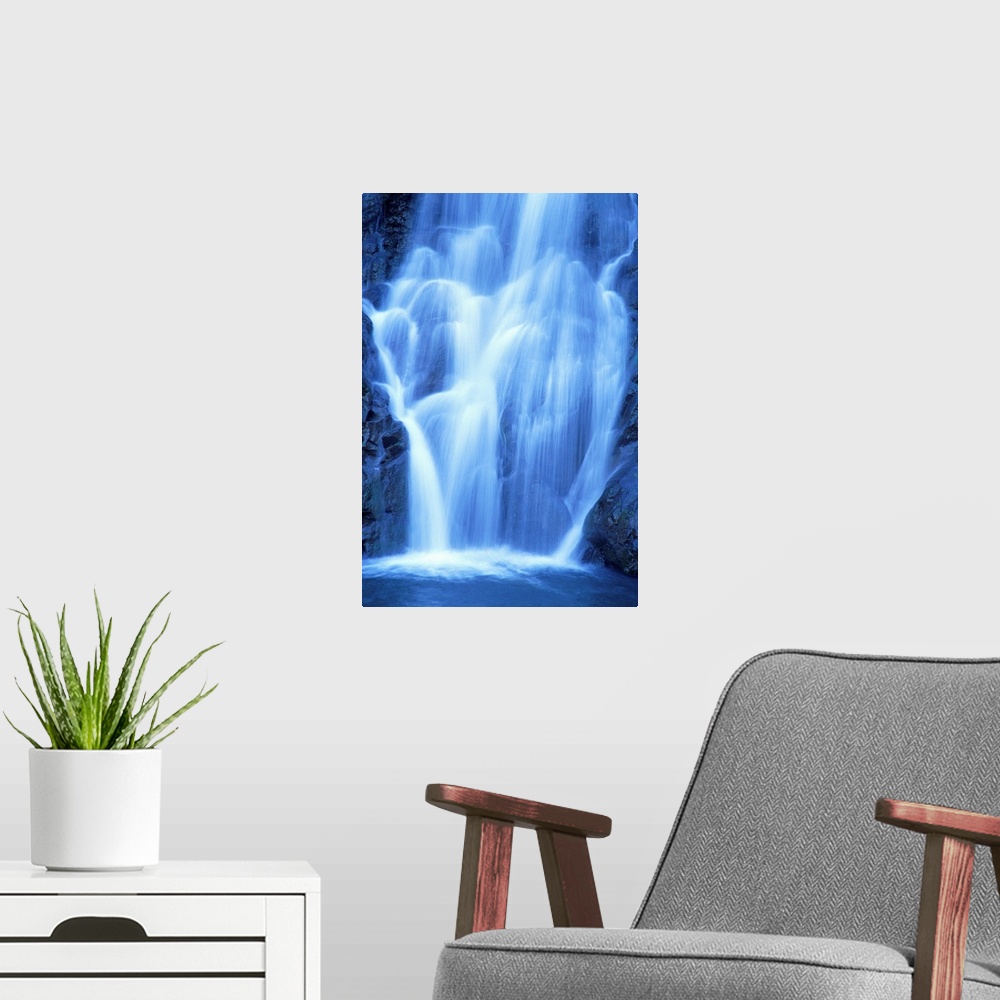 A modern room featuring Vertical canvas of a big waterfall rushing down a rocky cliff in Hawaii.