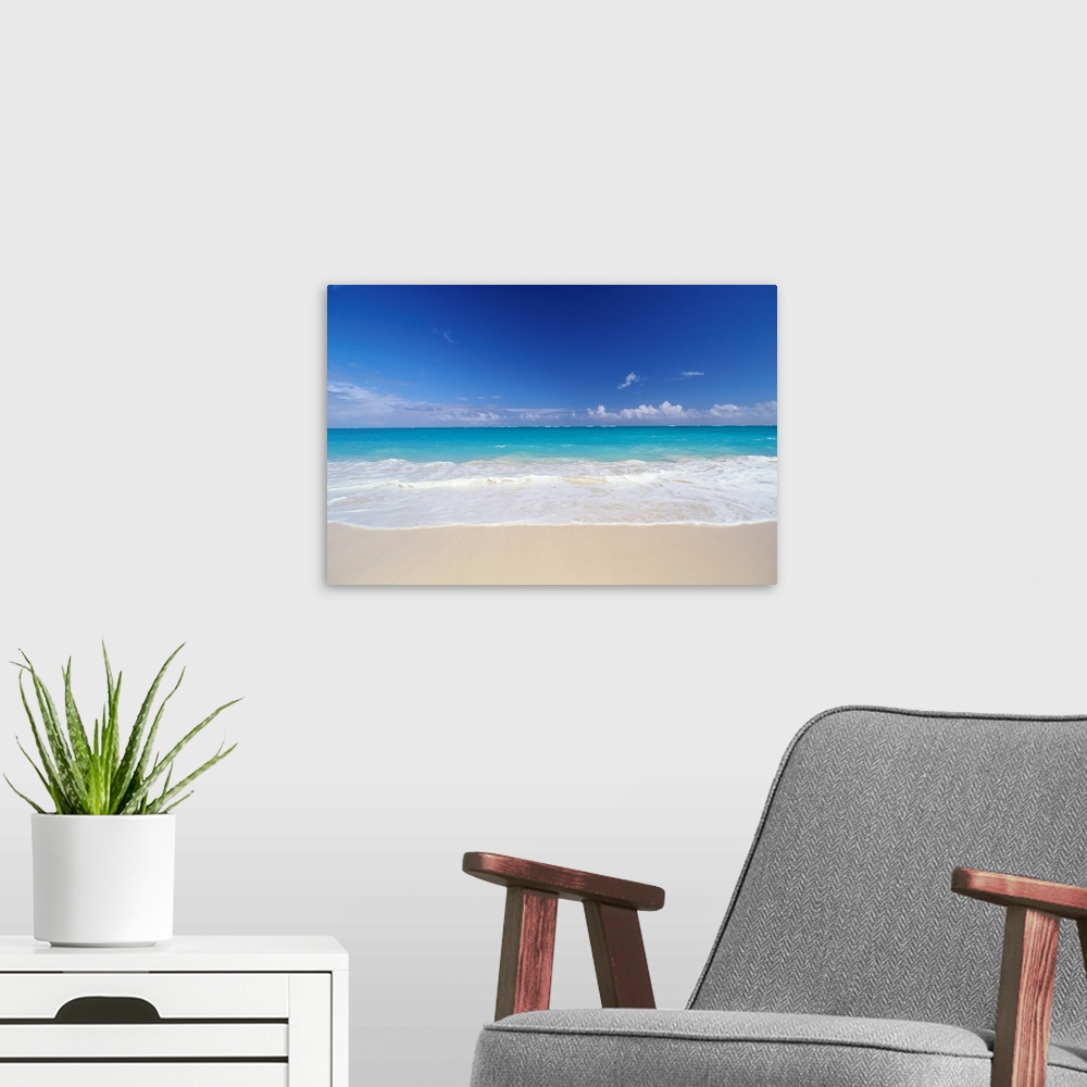 A modern room featuring Horizontal photograph on a big canvas of bright turquoise ocean water, crashing into the sand on ...
