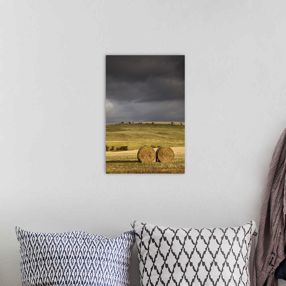 A bohemian room featuring Hay Bales In A Field Under A Dark Cloudy Sky; Northumberland, England