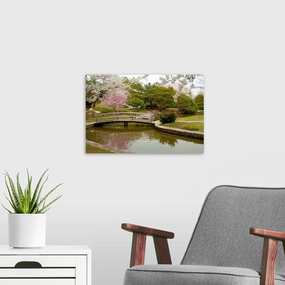A modern room featuring Large canvas photo art of a bridge crossing a river with flowering Japanese trees sprinkled aroun...