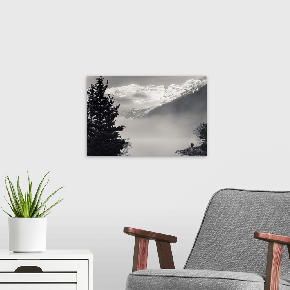 A modern room featuring Silhouette of a photographer on the shore of Lake Louise with fog rising from the lake at sunrise...