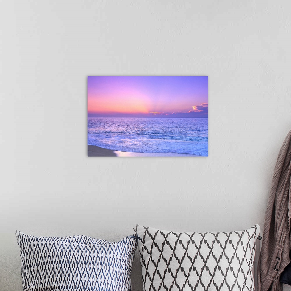 A bohemian room featuring A breathtaking photograph of a sunset over the vast ocean giving the overall picture a soft color...