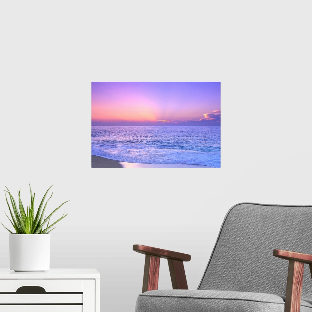 A modern room featuring A breathtaking photograph of a sunset over the vast ocean giving the overall picture a soft color...