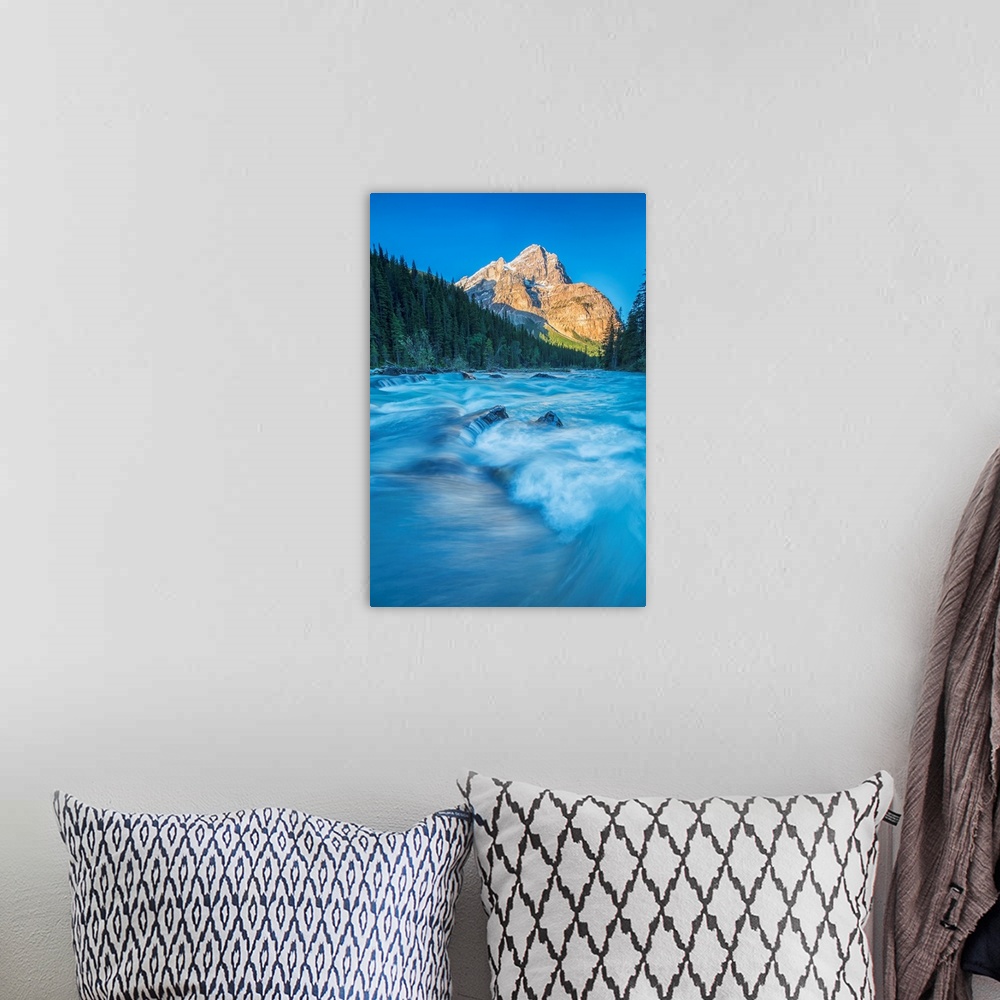 A bohemian room featuring Mount Stephen lights up as the sun rises while the Yoho river flows by, Yoho National Park, Canada.