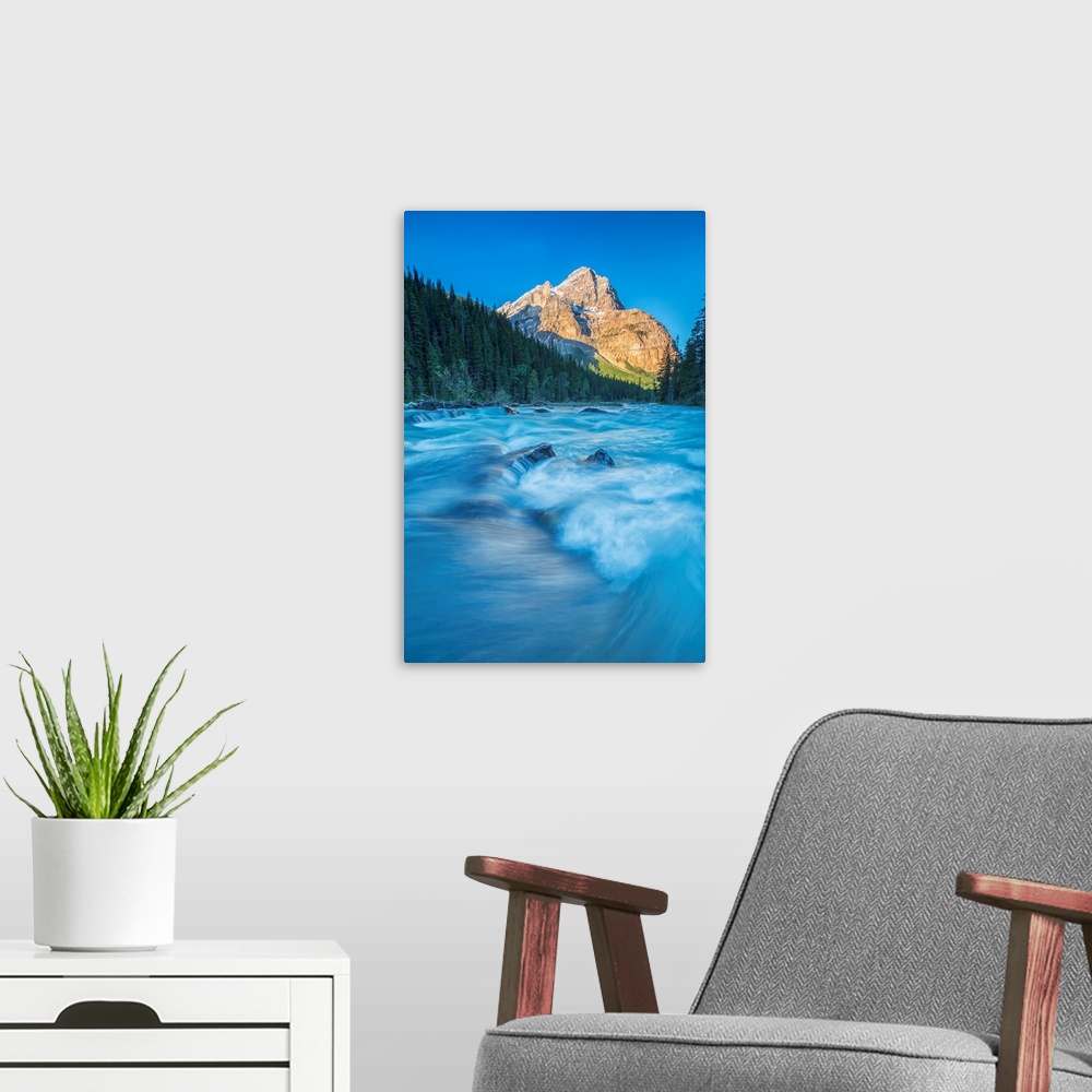 A modern room featuring Mount Stephen lights up as the sun rises while the Yoho river flows by, Yoho National Park, Canada.