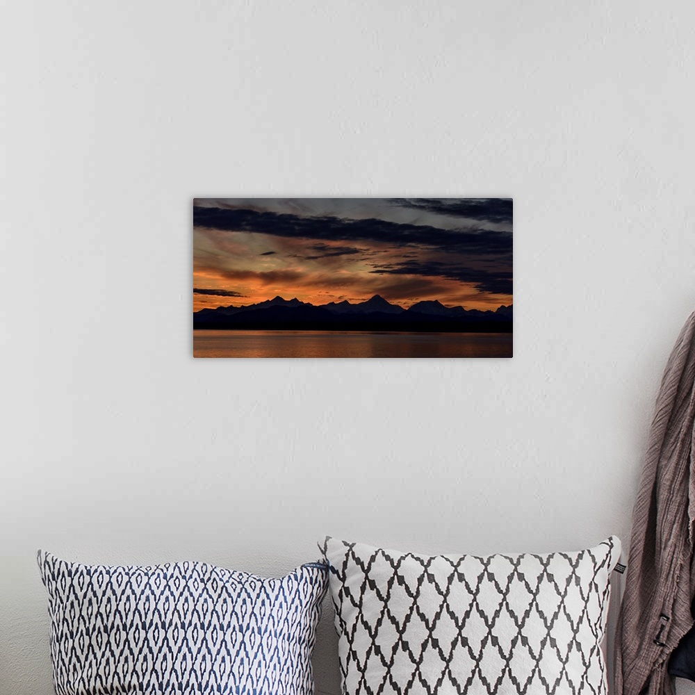 A bohemian room featuring Mountain peaks silhouetted at sunrise, with a dramatic red glowing sky with dark clouds in Glacie...