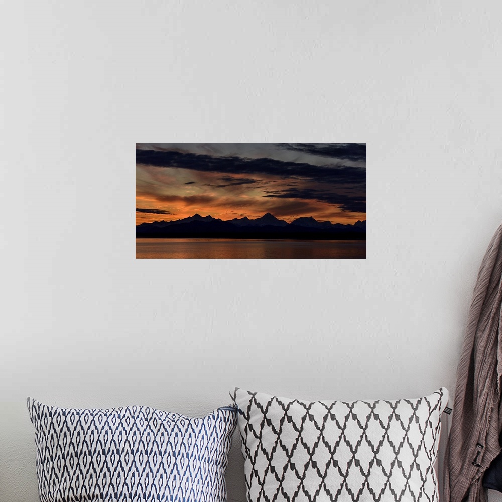 A bohemian room featuring Mountain peaks silhouetted at sunrise, with a dramatic red glowing sky with dark clouds in Glacie...