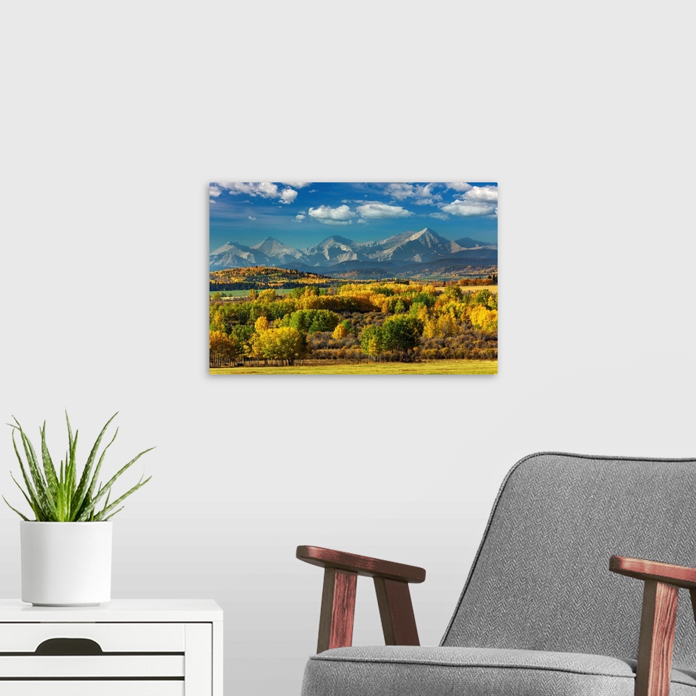A modern room featuring Mountain range with colourful covered treed foothills in the fall with blue sky and clouds, West ...