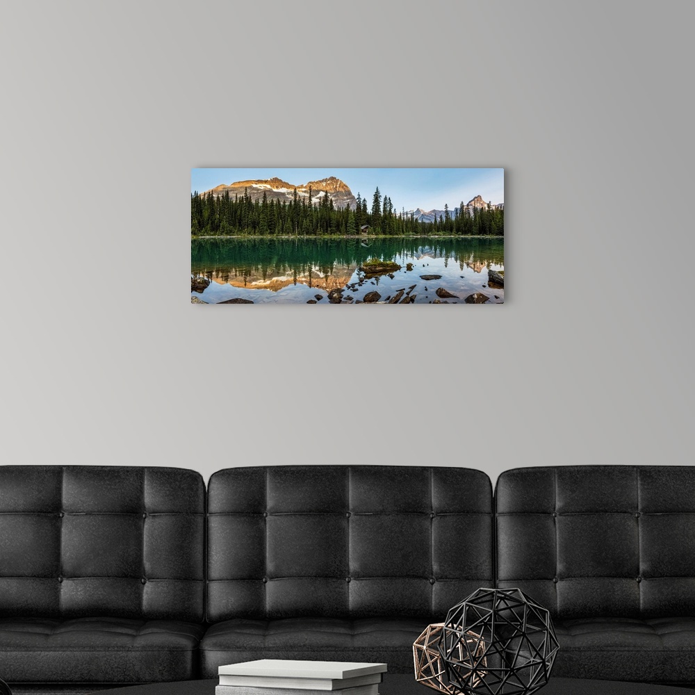 A modern room featuring Panorama of mountain range reflecting in an alpine lake with the glow of warm early morning light...