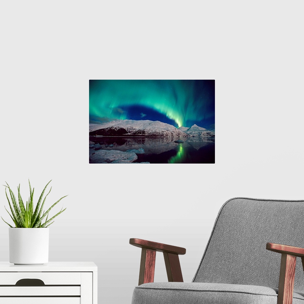 A modern room featuring Canvas photo art of northern lights in the sky above snow covered mountains near water.