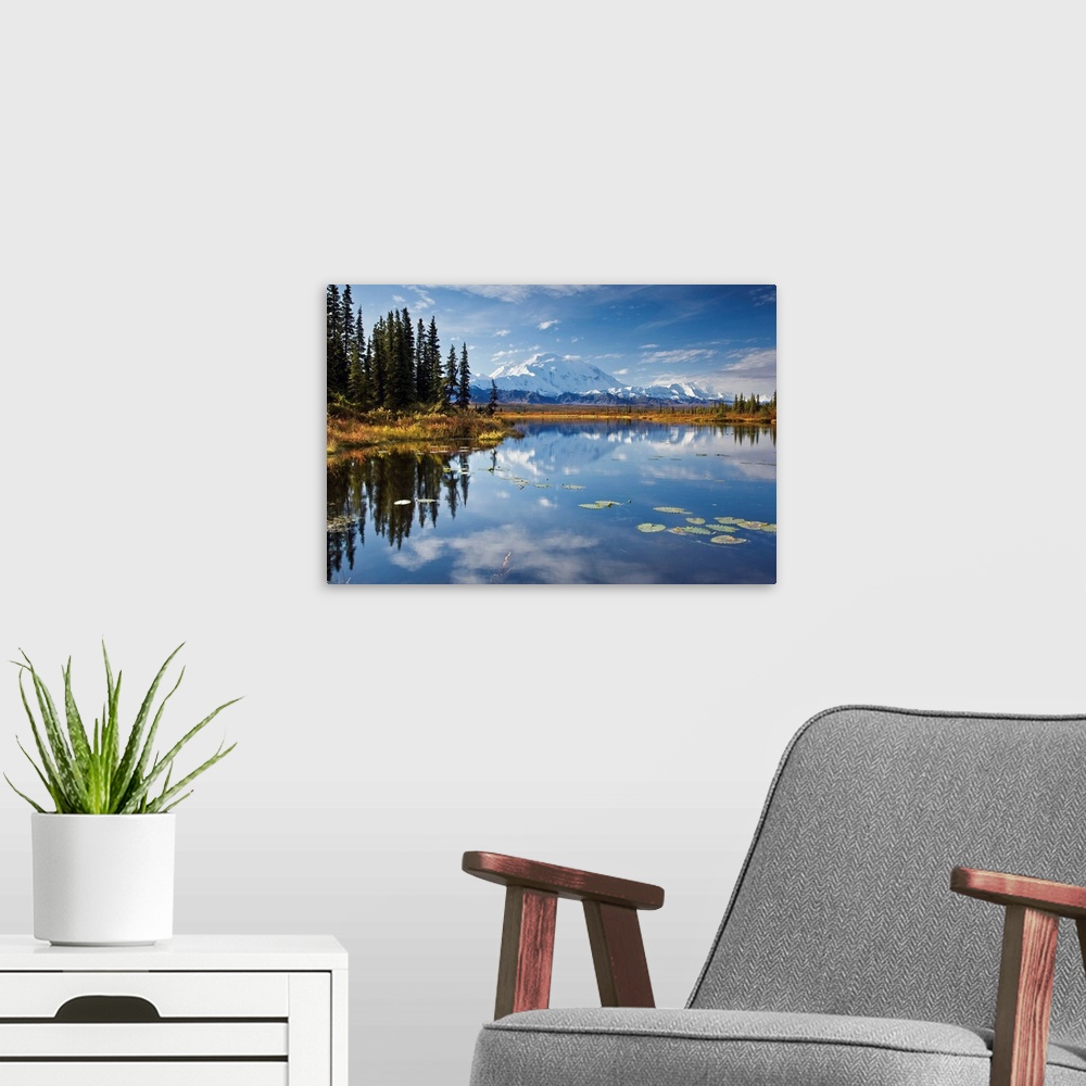 A modern room featuring This is a landscape photograph of the Alaskan sky, trees, and mountains mirrored in still waters.