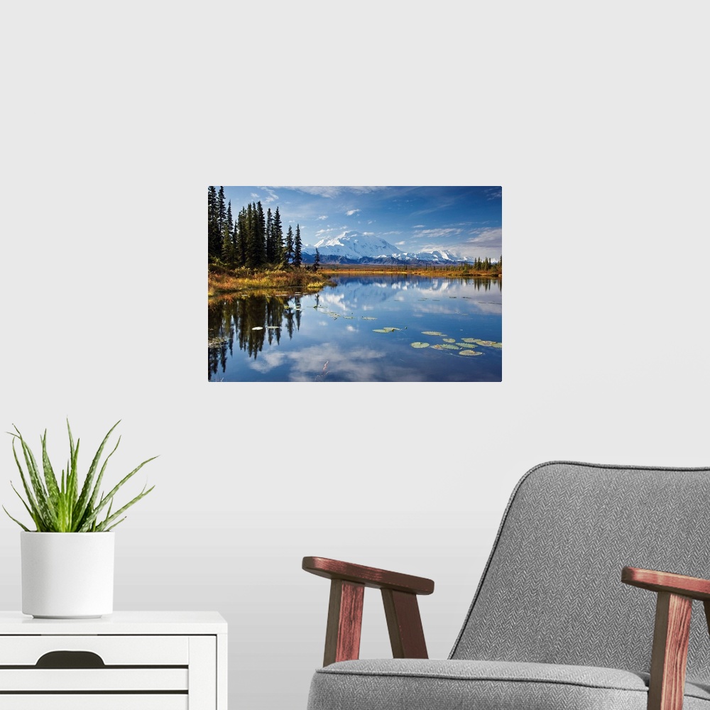 A modern room featuring This is a landscape photograph of the Alaskan sky, trees, and mountains mirrored in still waters.