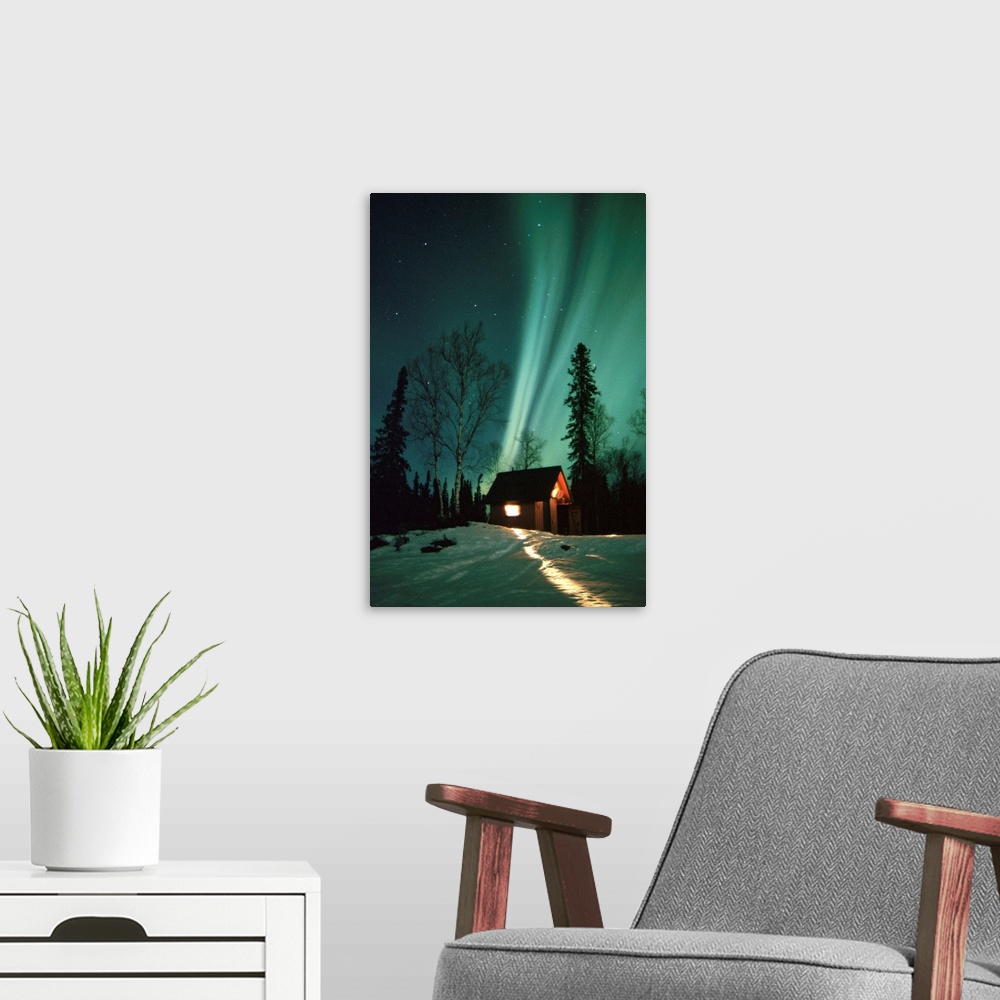 A modern room featuring A photograph of the Aurora Borealis wisps in starry sky above a small cabin in the snow.