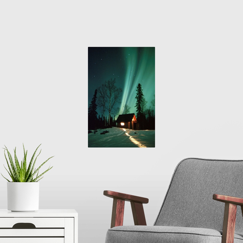 A modern room featuring A photograph of the Aurora Borealis wisps in starry sky above a small cabin in the snow.