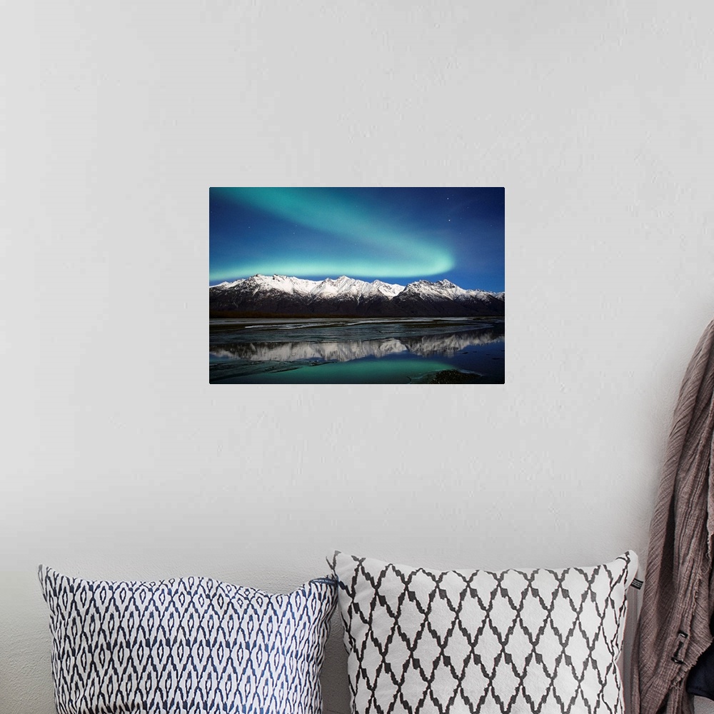 A bohemian room featuring A landscape photograph of the aurora borealis and mountains reflecting in a lake filled with ice.