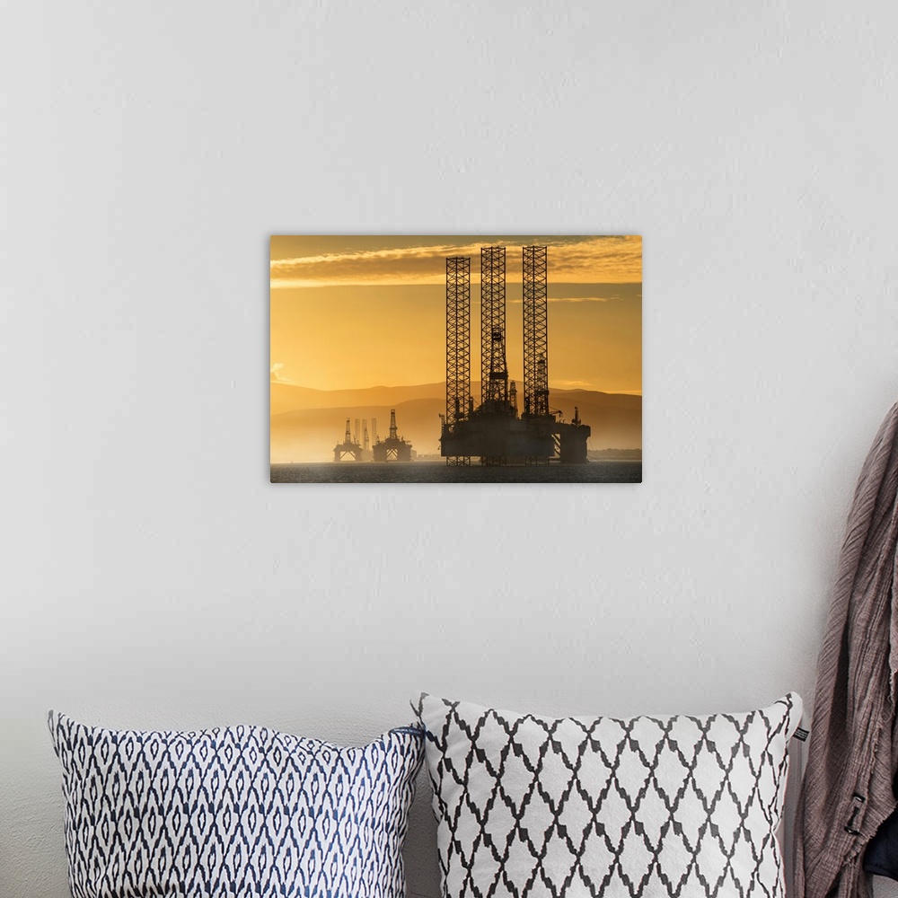 A bohemian room featuring Oil drilling rigs out in the ocean with a view of the coastline and golden sunset; Cromarty, Inve...